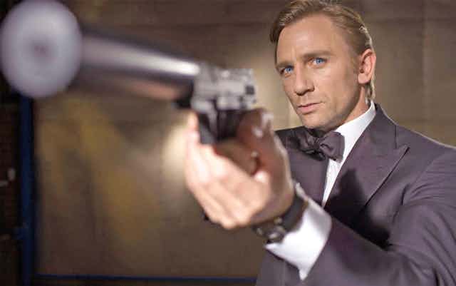 Daniel Craig as James Bond points a gun towards the camera.