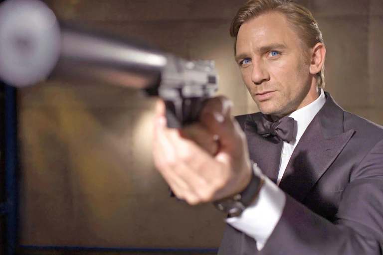 Daniel Craig as James Bond points a gun towards the camera.