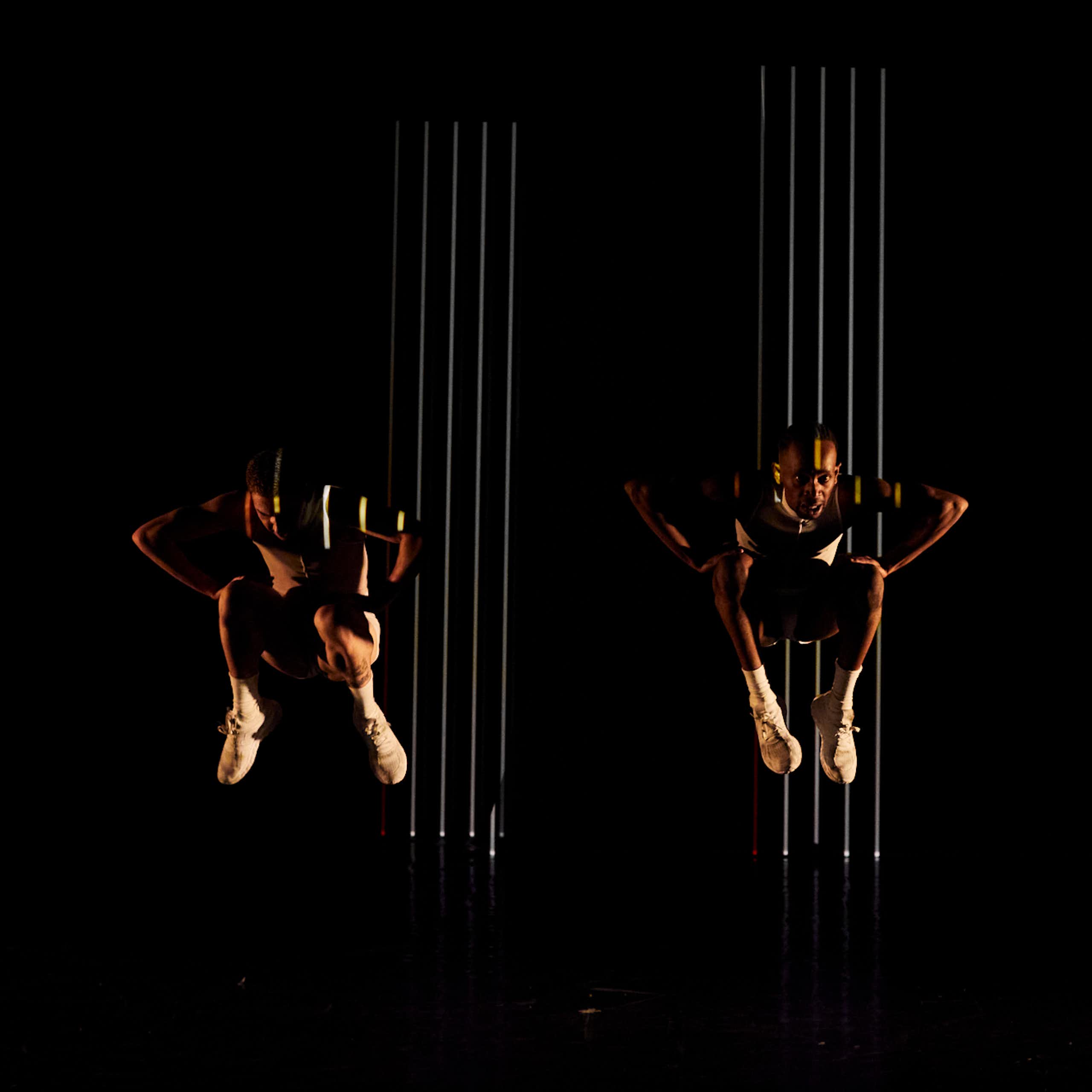 Three dancers against a black backdrop, suspended in the air.