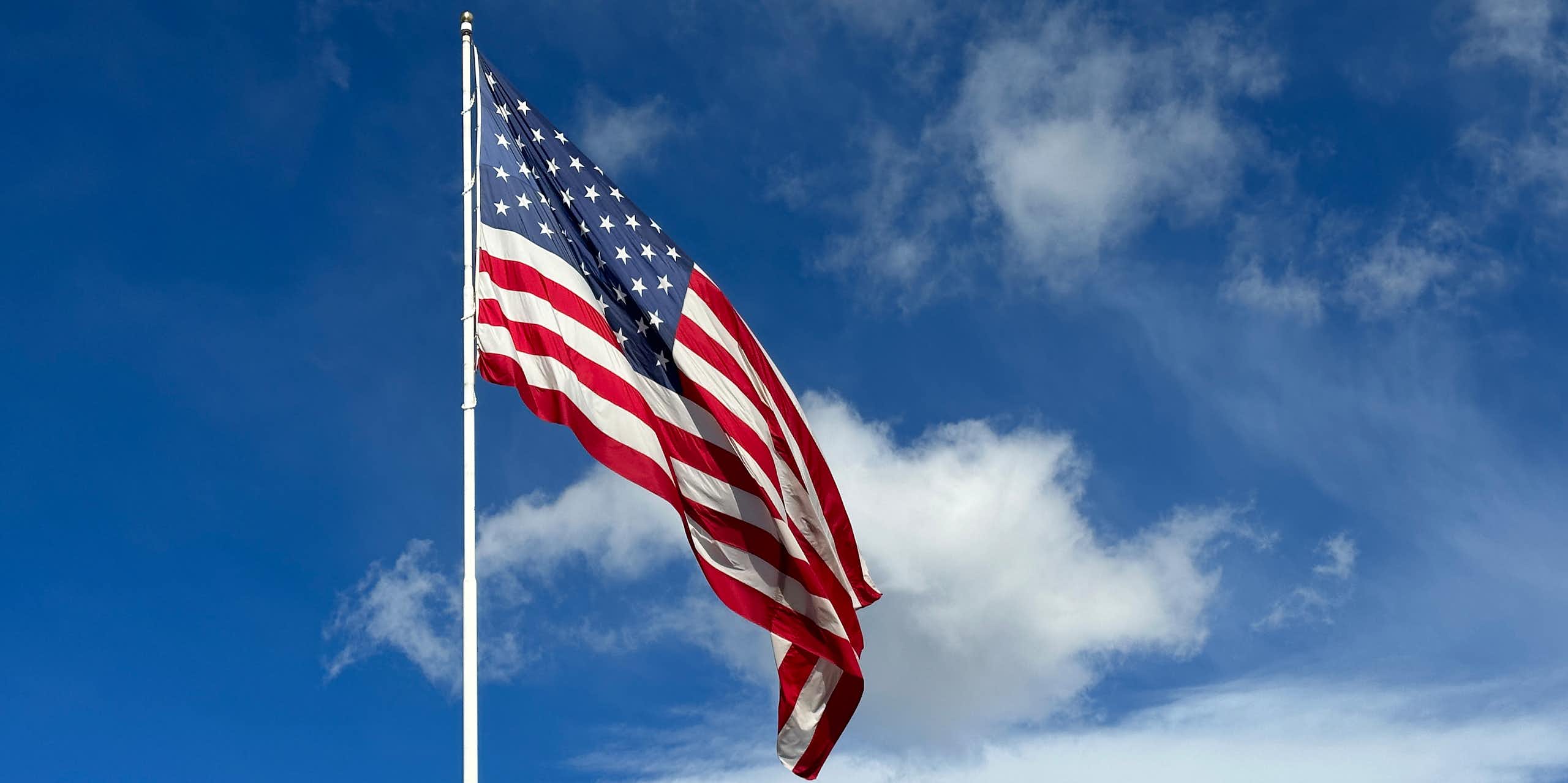 An American flag fluttering against a cloudy sky.