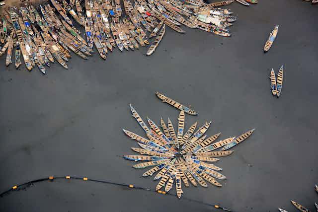 aerial shot of small wooden fishing boats moored up together, grey sea