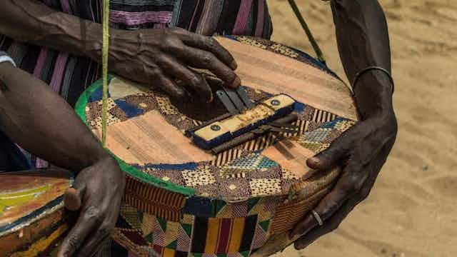 Deux mains jouant d'un instrument de musique traditionnel.
