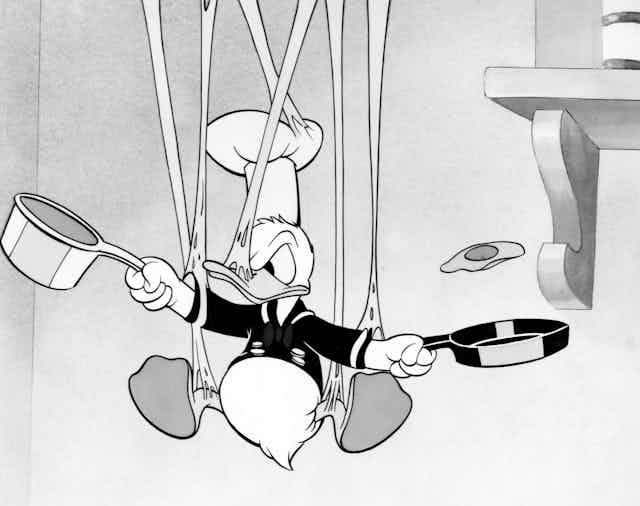O Pato Donald em preto e branco em uma bagunça enquanto tenta cozinhar. 