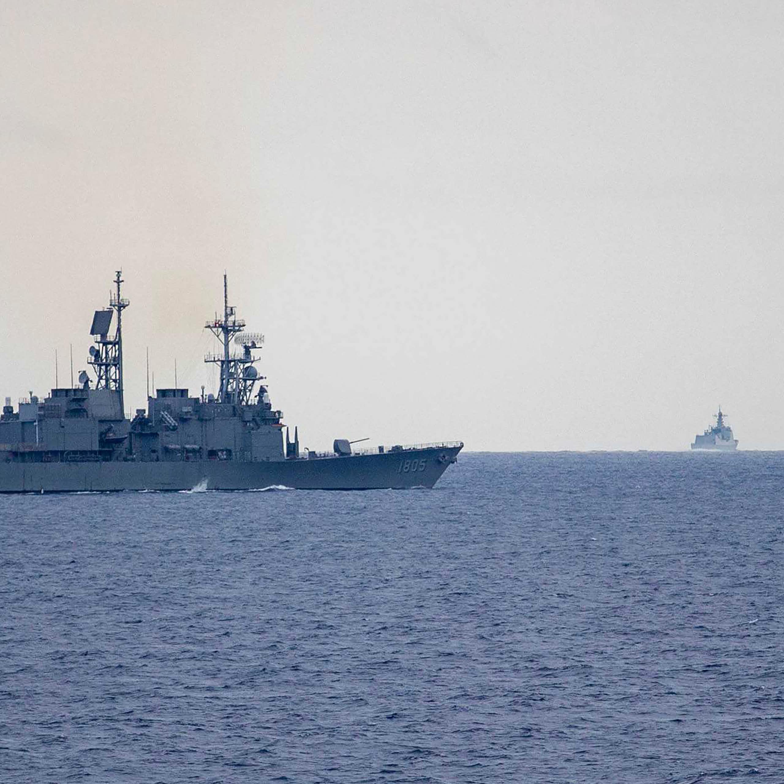 Two military destroyers, one further off on the horizon.