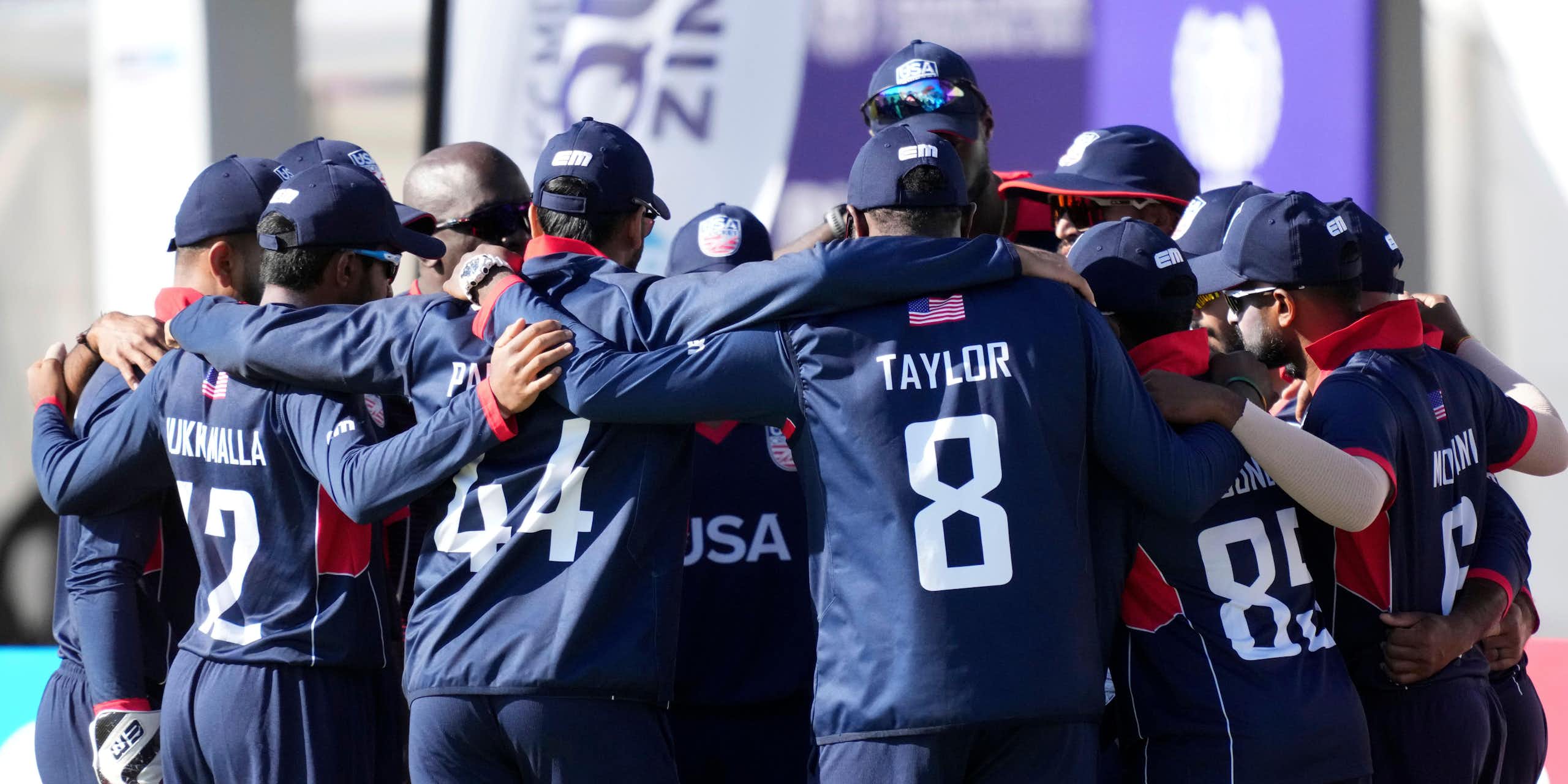 The men's USA cricket team gathered together in a huddle.