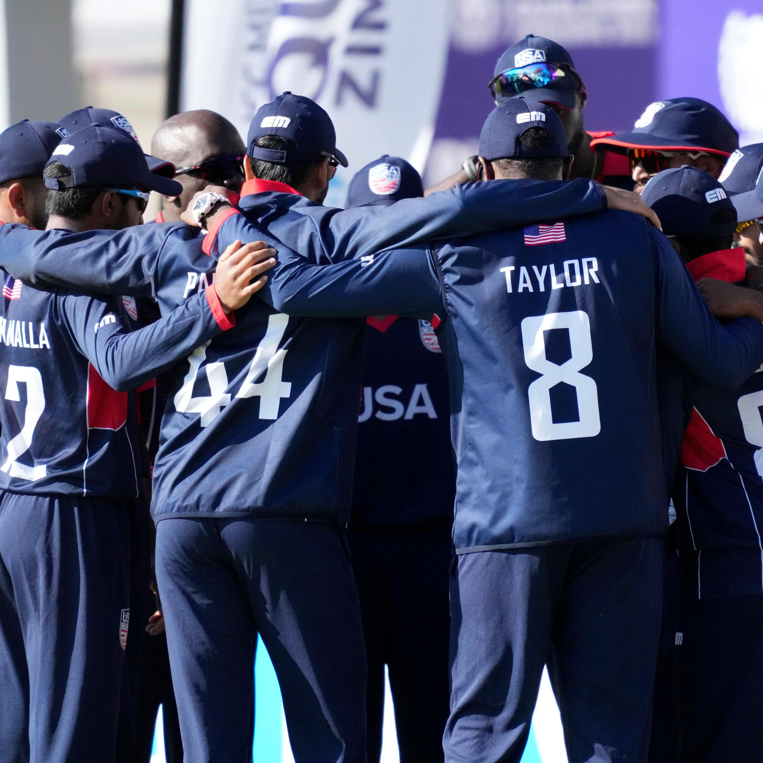 The men's USA cricket team gathered together in a huddle.