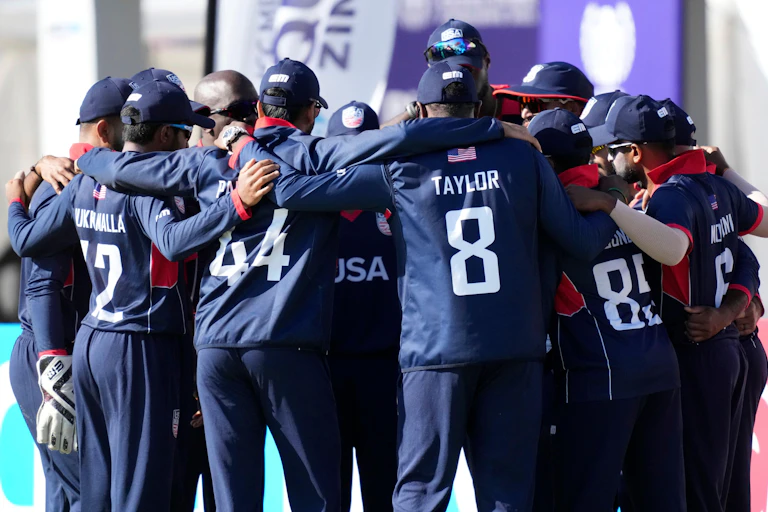The men's USA cricket team gathered together in a huddle.