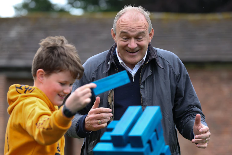 Liberal Democrat leader Ed Davey playing jenga with a child.