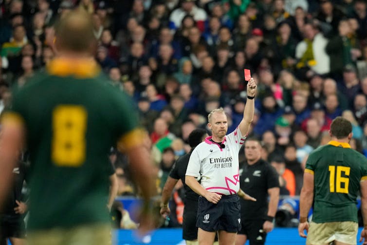 Rugby union referee holding up a red card to send off a player