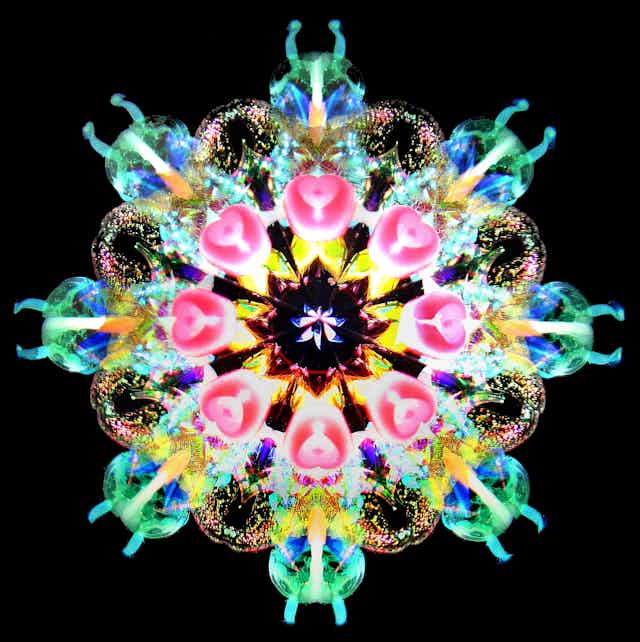 view into a kaleidoscope showing a flower-petal-like arrangement of eight segments, each showing multicolored shapes