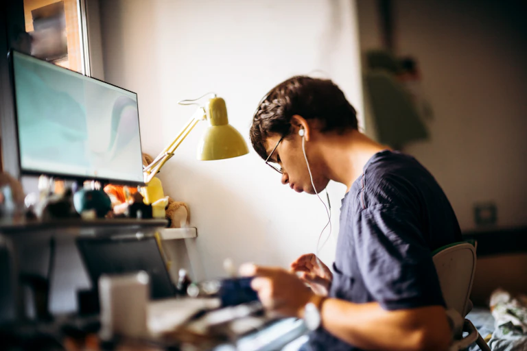 young man sits at computer with headphones on