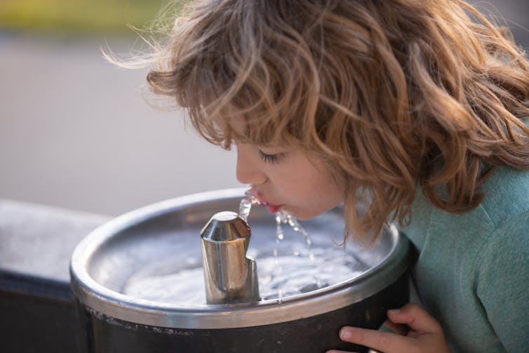 child at water fountain outdoors
