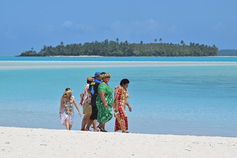 a group of people walk along beach
