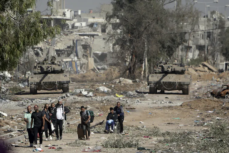 Palestinians on a road with damaged buildings in Gaza.
