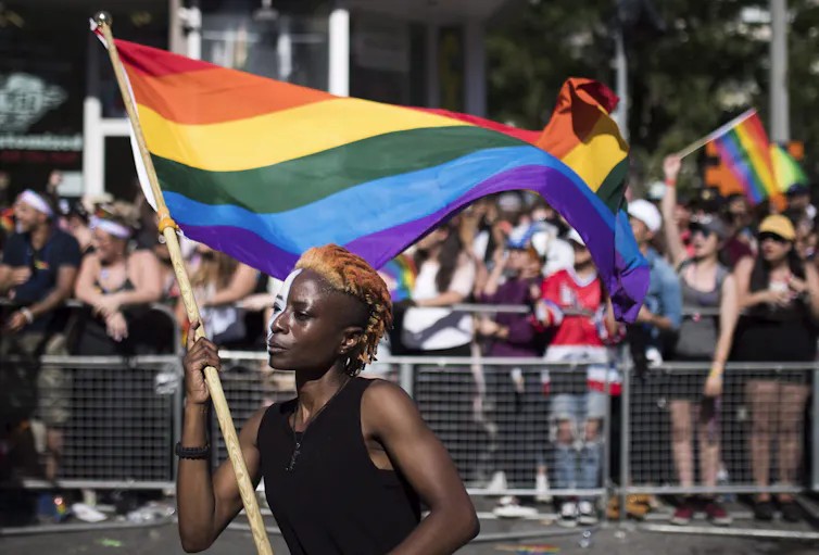 A woman carries a rainbow flag on a poll at a pride march