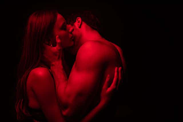 A man and a woman in red light kissing