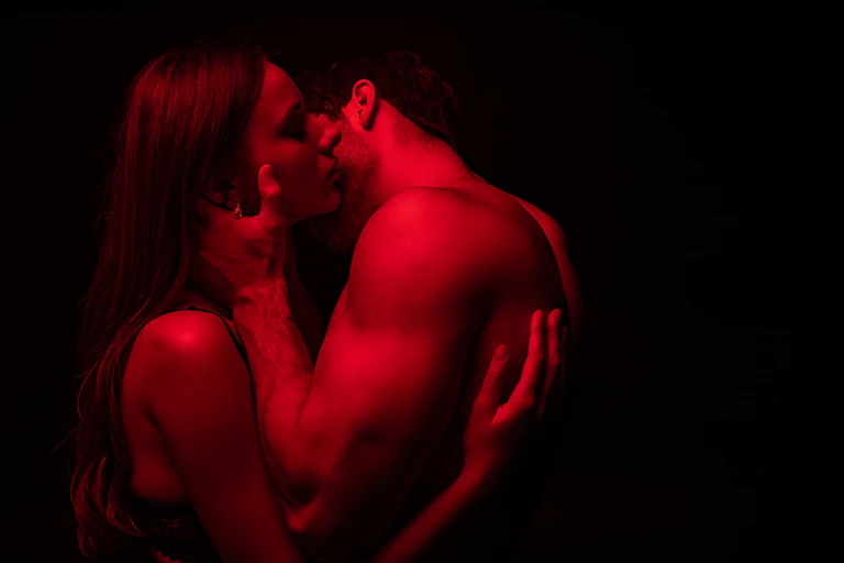 A man and a woman in red light kissing