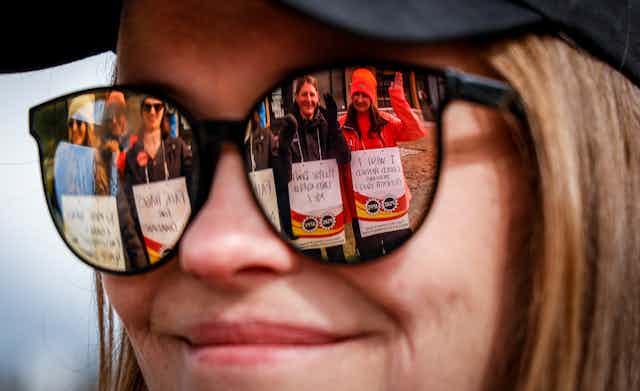 Pickering public service workers are reflected in a smiling woman's sunglasses.