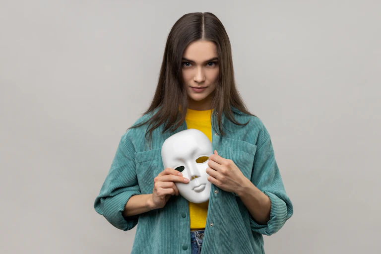 Portrait of a serious woman with dark hair holding a white mask