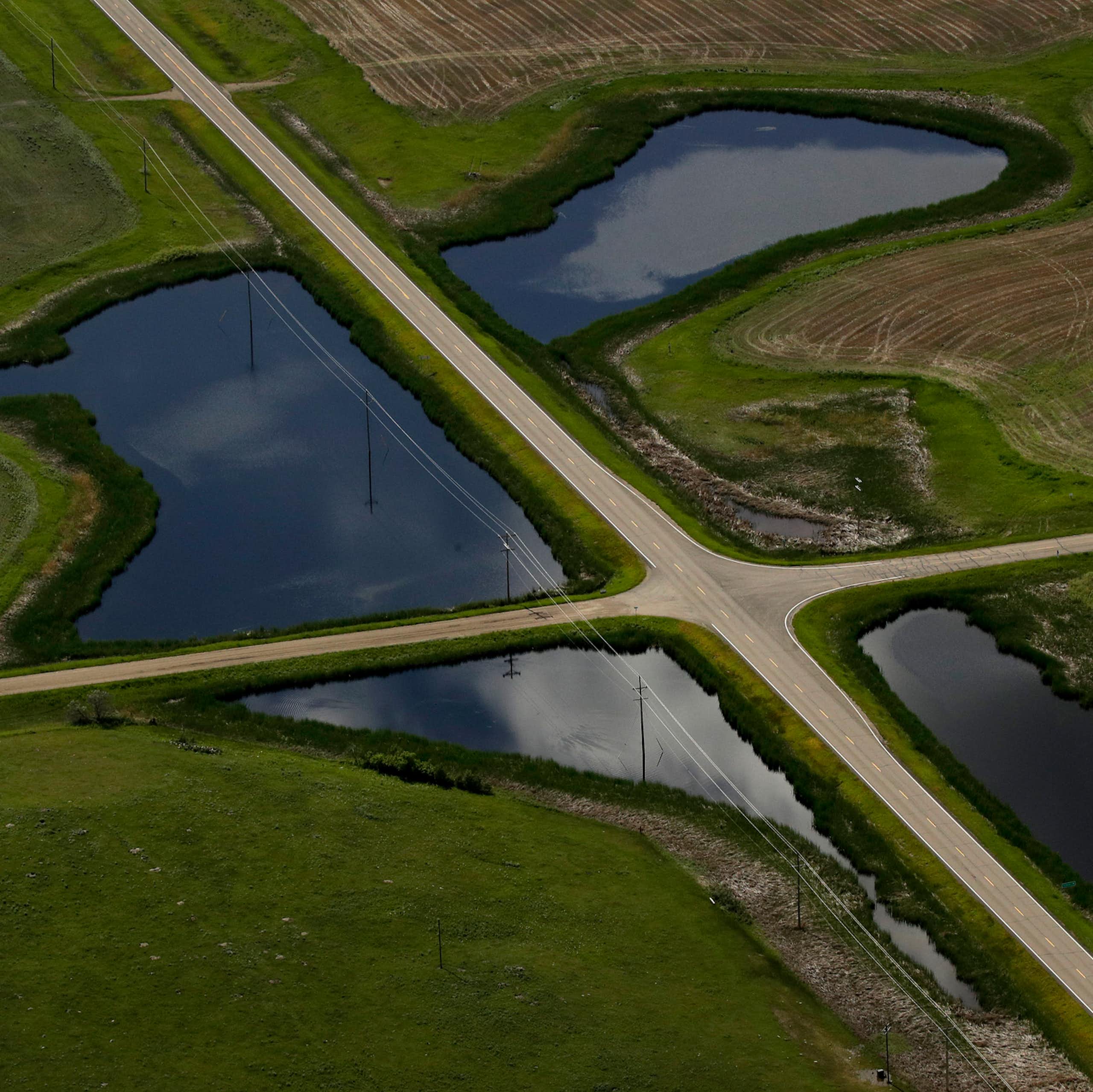 Two roads intersect, dividing a large pond into four smaller sections