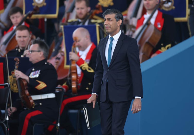 Rishi Sunal em um evento, passando por uma banda militar.