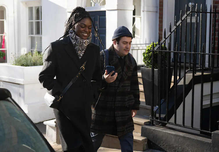 Lucy and Austin walk down a London street.