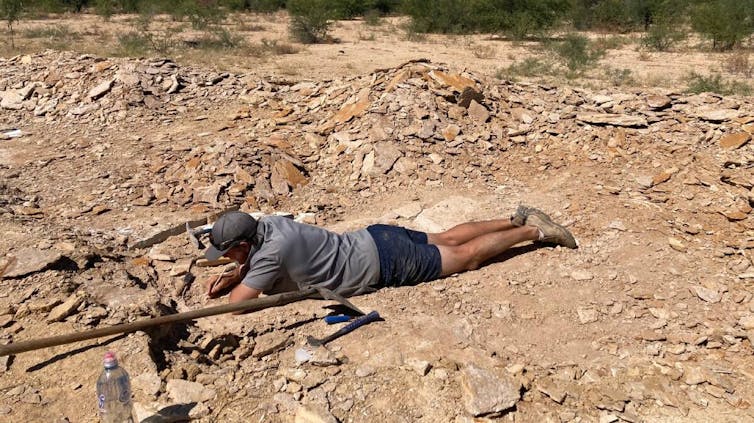 Photo of a man lying prone digging in dirt