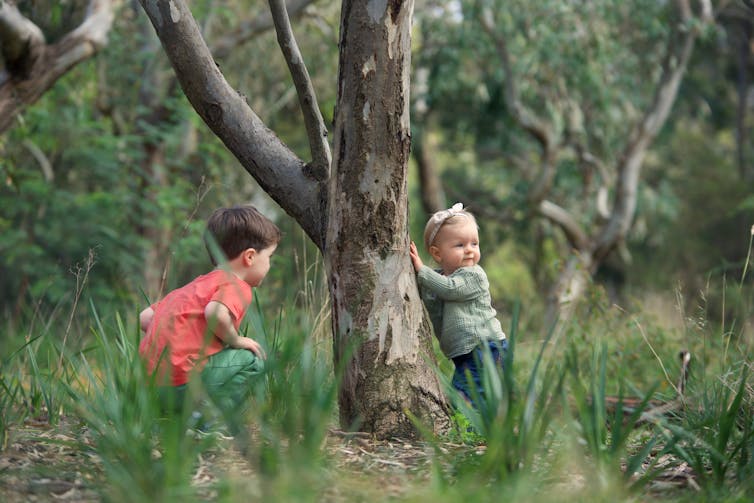 young children playing around tree