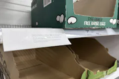 Cases of egg cartons seen empty on supermarket shelf.