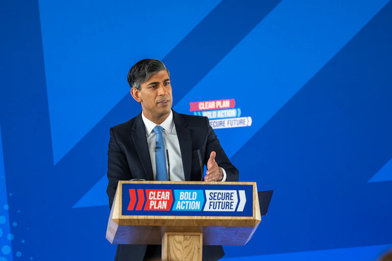 The British prime minister at a lecturn on stage.