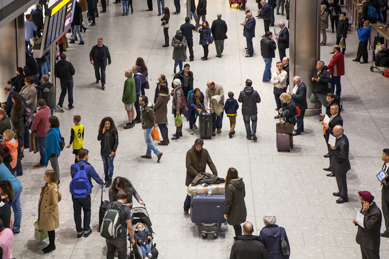 Wide view of people with luggage and bags walking around an airport terminal