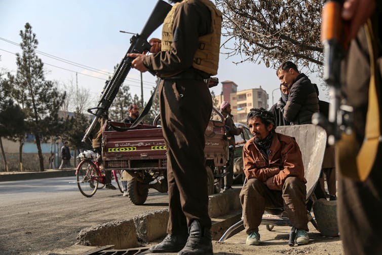 An armed guard standing next to a road as people watch on.