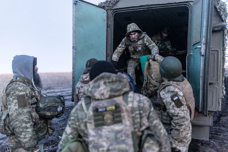 A man in fatigues unloads a baf from a truck.