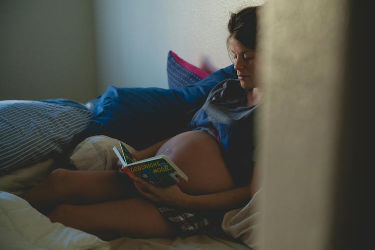 Pregnant woman reads in bed