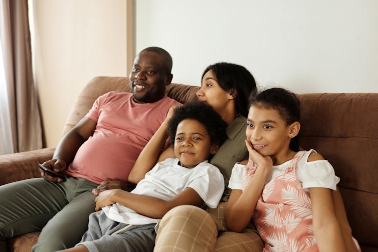 A man, woman and two children snuggle on a couch.