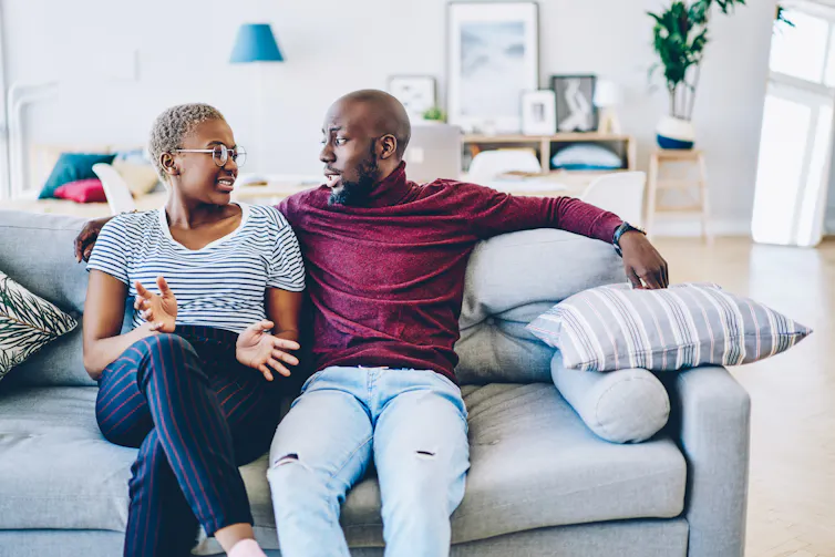 A couple talking on a couch.
