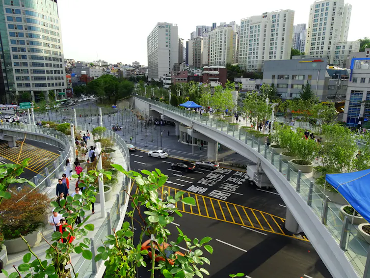 A treed walkway running through the heart of a city of skyscrapers