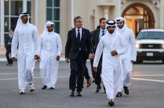 US secretary of state, Antony Blinken, walking surrounded by Qatari men in dressed in traditional Arab clothing.