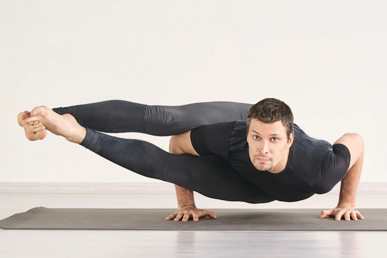 Un homme fait une posture de yoga difficile