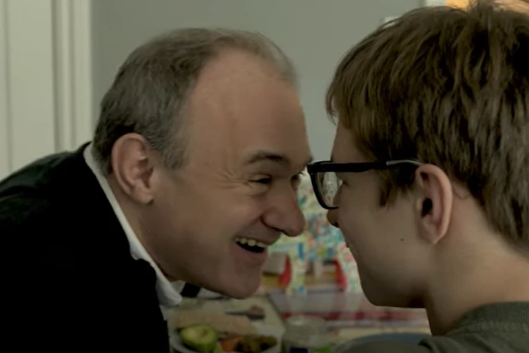 Clip of Ed Davey smiling and touching foreheads with his teenage son John, at home