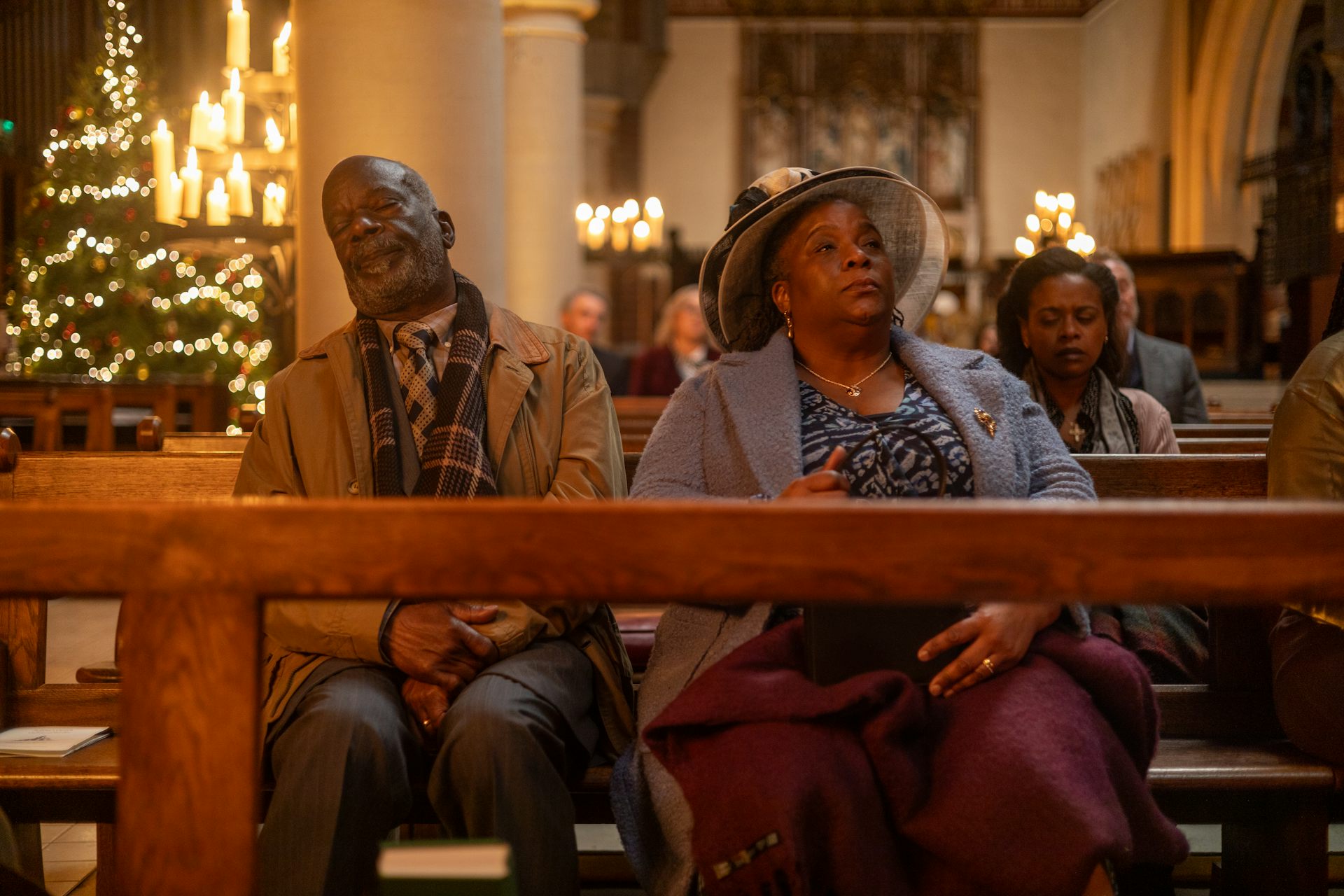 An elderly couple sitting in a church, the grandfather is asleep.