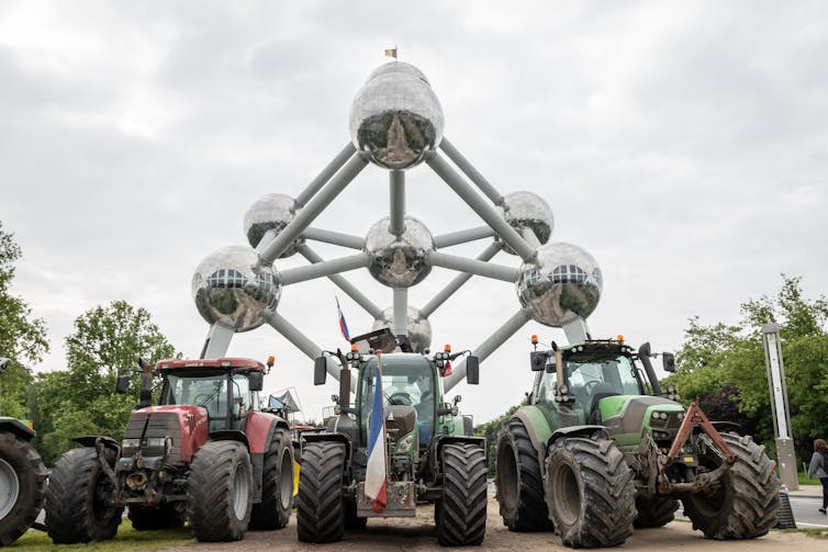 tractors in front of large sculpture