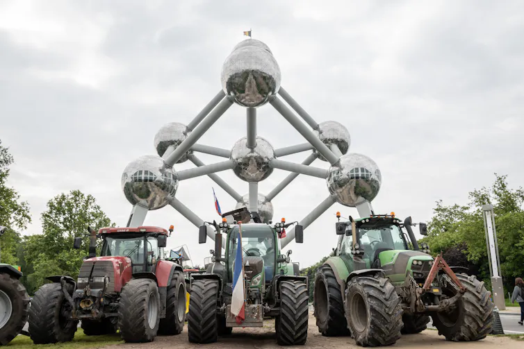 tractors in front of large sculpture