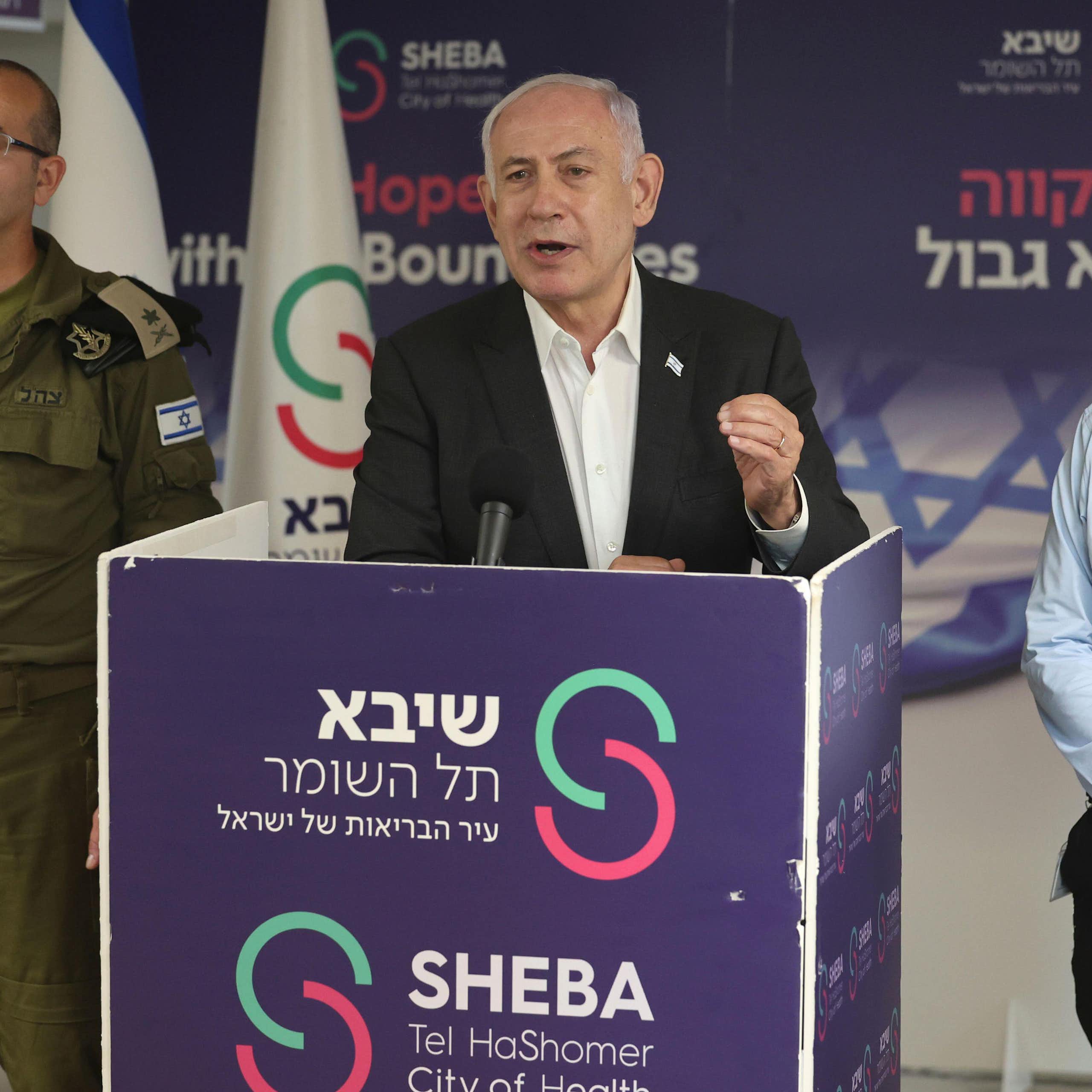 Israeli prime minister Benjamin Netanyahu delivers a speech from a podium, flanked by a military and a political aide.