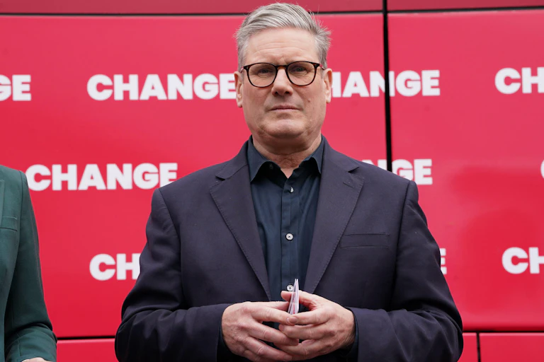 Keir Starmer in front of a bus that has the word 'change' printed on it many times.