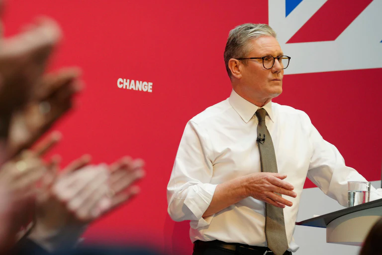 Keir Starmer giving a speech in front of the word 'change' printed on a wall