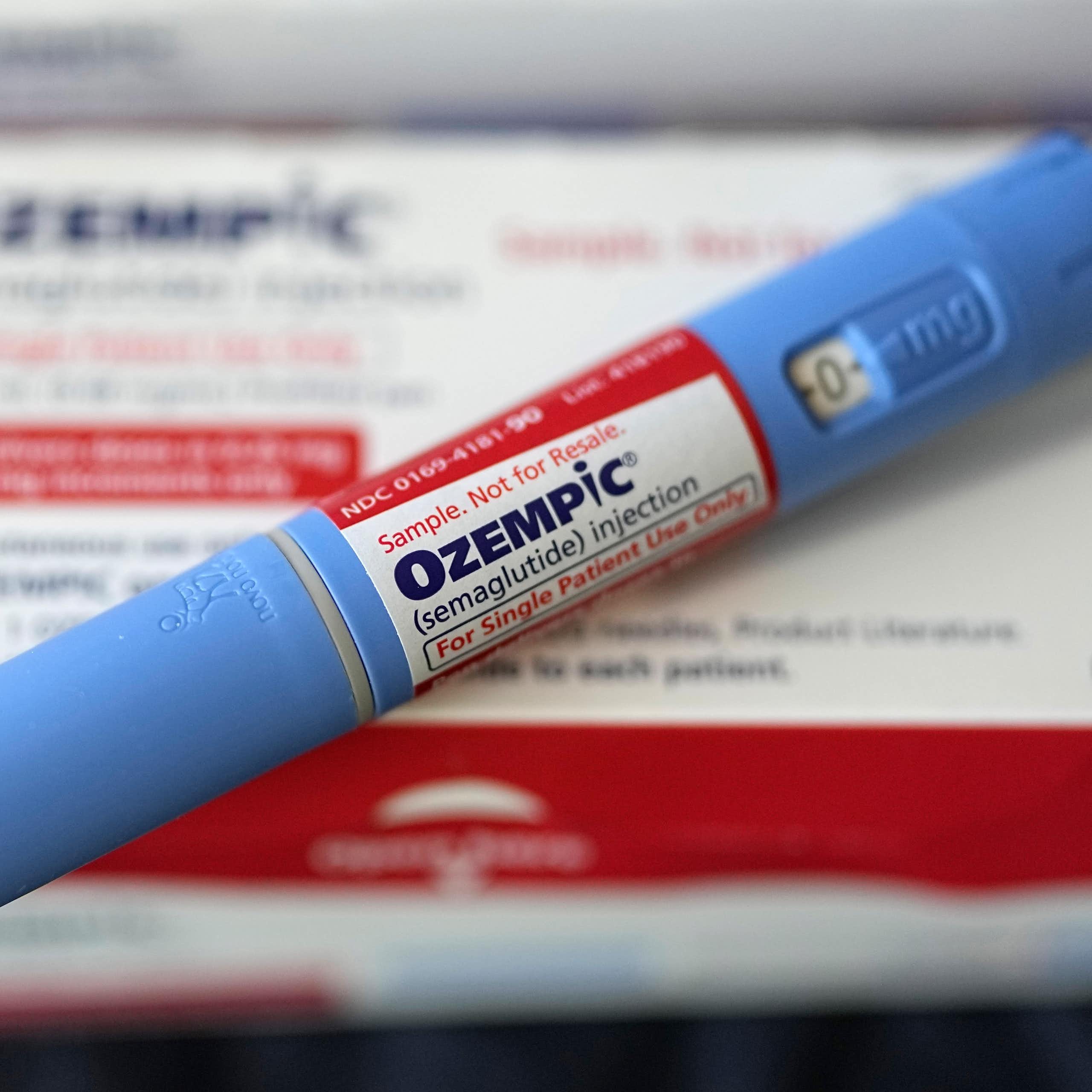 An injectable Ozempic pen rests diagonally across a drug package. 