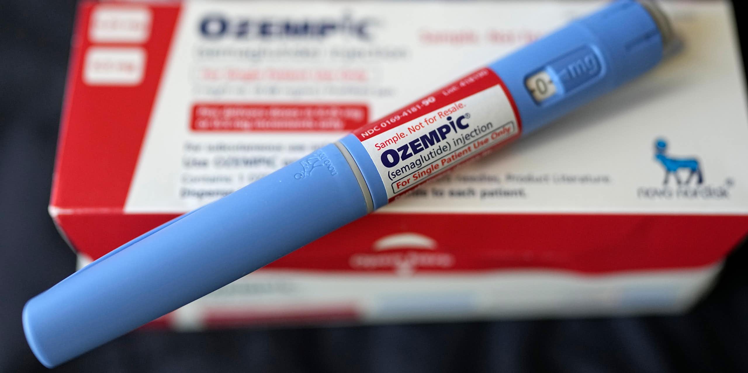 An injectable Ozempic pen rests diagonally across a drug package. 