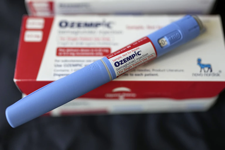 An injectable Ozempic pen rests diagonally across a drug package.