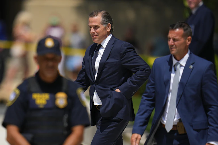 man in suit walking with blurry law enforcement officer in foreground